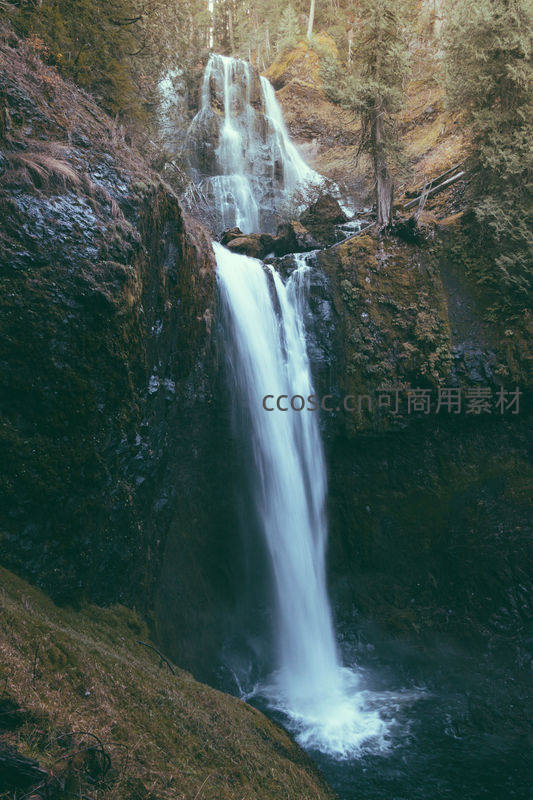深谷飞瀑倾泻而下，水雾氤氲绿意盎然