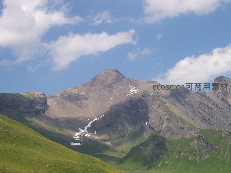 绿坡环抱山峦，残雪点缀苍茫峰顶