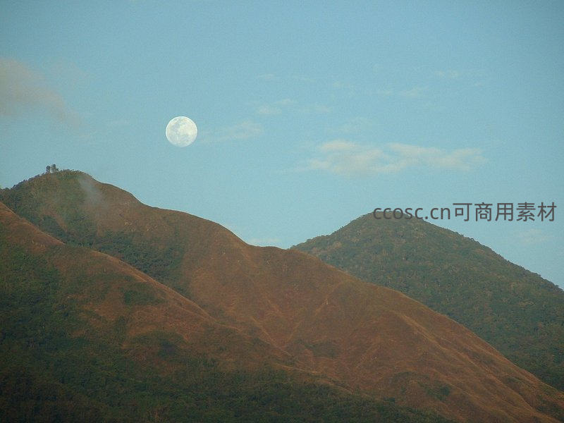 明月高悬山巅，暮色笼罩起伏丘陵