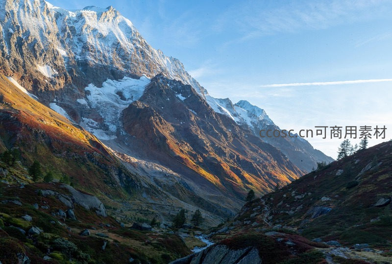 秋日山谷阳光洒满雪峰与彩林
