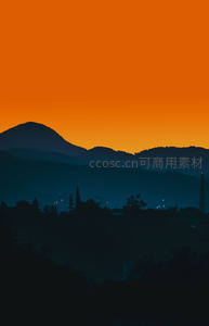 橙色天空下的山峦剪影与城市灯火