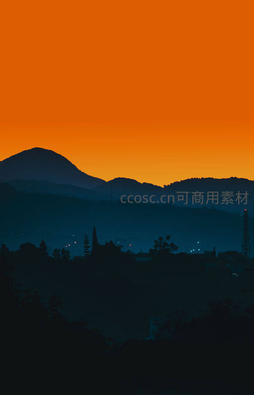 橙色天空下的山峦剪影与城市灯火