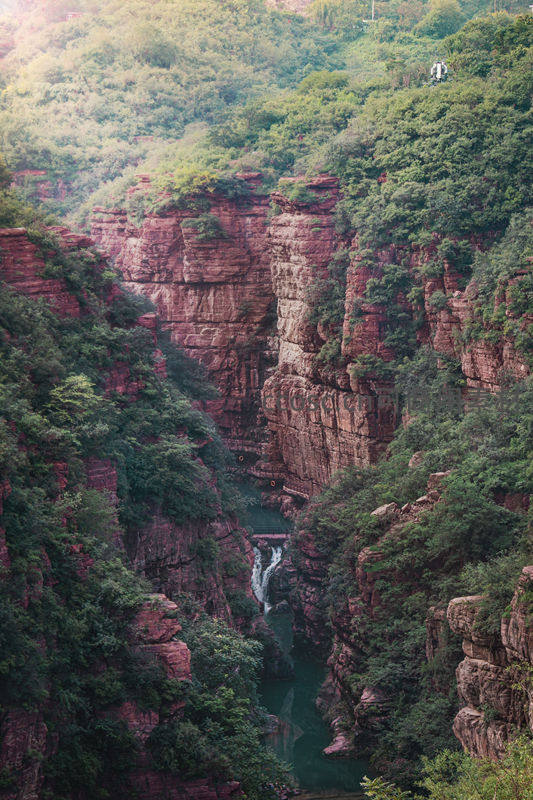 红岩峡谷中的碧水瀑布与绿树