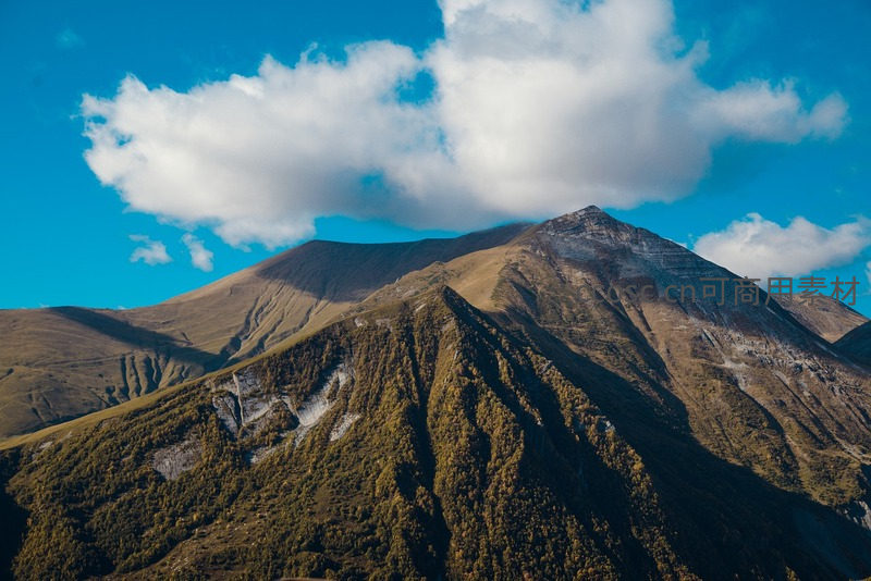蓝天白云下雄伟山峰巍然屹立