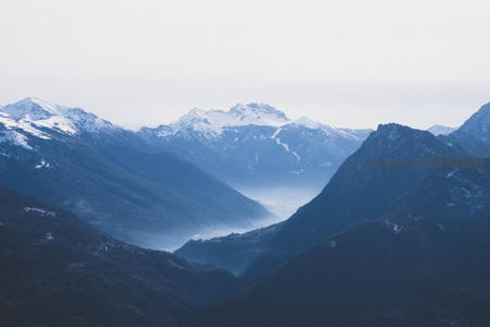 云雾缭绕群山间，雪顶峰峦若隐若现