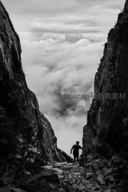 黑白影像中行人穿行云海裂谷之间