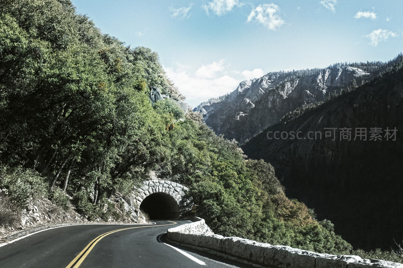 蜿蜒山路穿过绿树掩映的石拱隧道