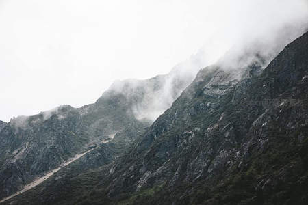 云海翻涌遮蔽山巅，岩壁陡峭植被稀疏