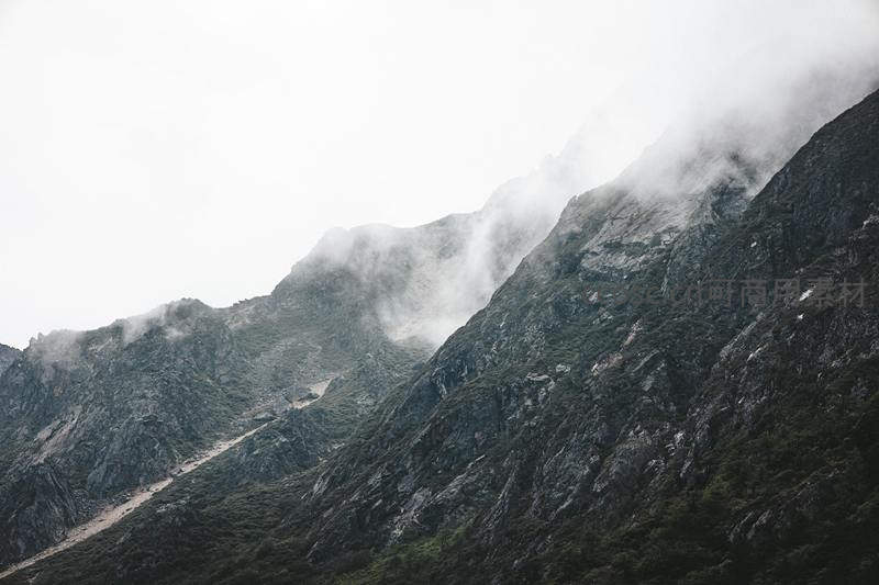云海翻涌遮蔽山巅，岩壁陡峭植被稀疏
