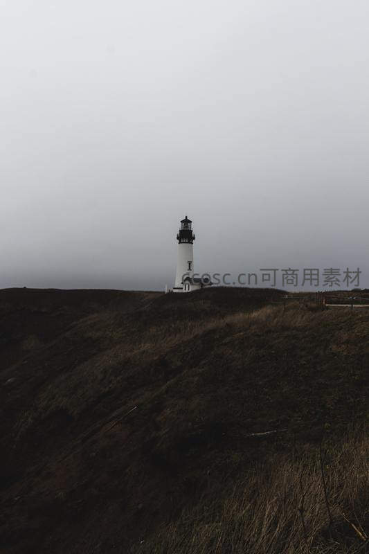 孤寂灯塔伫立在雾霭笼罩的山丘