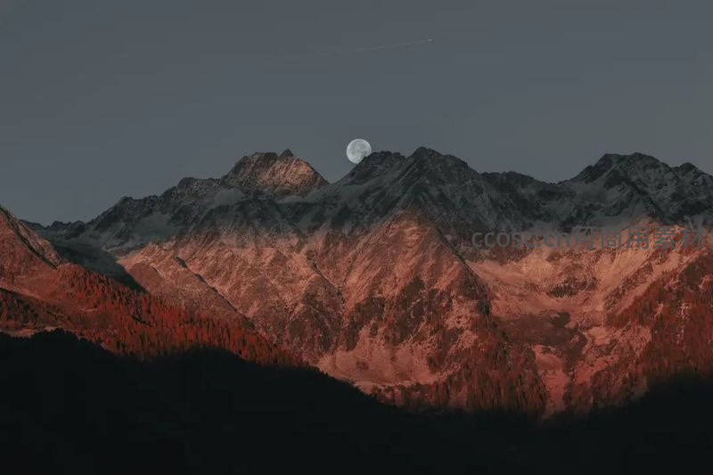 月升山巅映照赤色峰峦