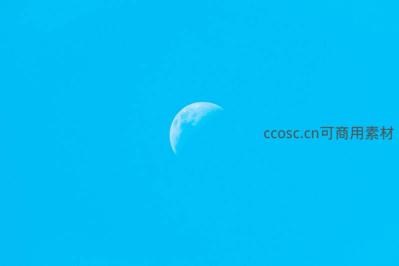 半轮明月悬于澄澈蔚蓝天空之中