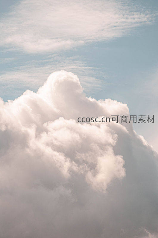 巨大蓬松云团在淡蓝天空中