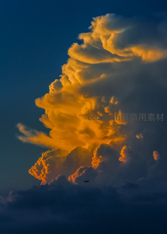 金色积雨云，飞机掠过天际