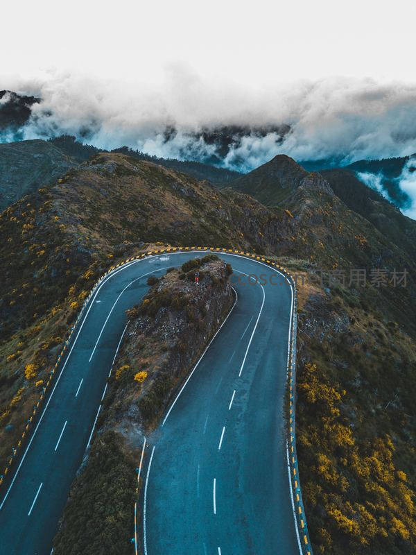 航拍蜿蜒山路穿梭于云雾缭绕山峦