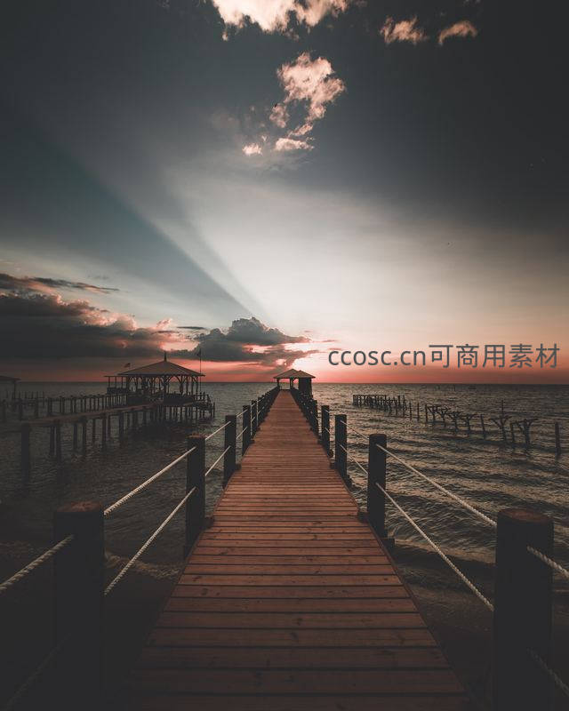 夕阳下的木质栈桥延伸至海天相接处