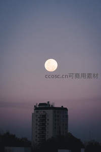 城市上空的皎洁明月与暮色