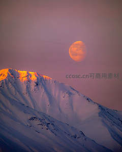 橙月映照雪山之巅，霞光染峰如焰