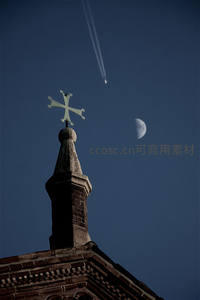 教堂尖顶与新月同框，天空划过飞机尾迹