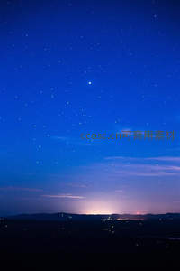 城市远光映衬深蓝夜空星辰
