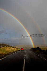公路尽头双彩虹下的红色汽车