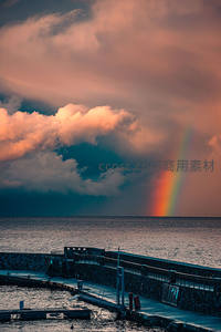 暮色海港旁彩虹穿透云层