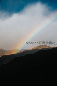 山巅彩虹划破云层，光影交织如梦似幻