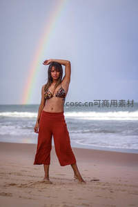 海滩女子在彩虹下伸展身姿