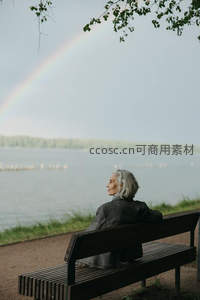 银发女士湖畔长椅静赏彩虹