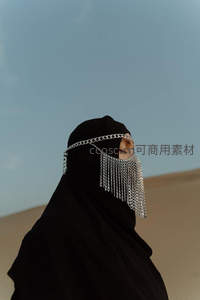 黑纱蒙面女子在沙漠中凝望远方