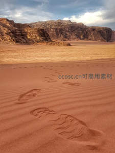 红色沙地上延伸的足迹通向岩壁