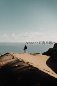 孤独旅人伫立沙丘之巅眺望无垠大海