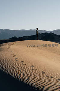 孤影立于沙丘眺望群山