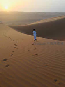 孩童踏着脚印奔跑于沙丘之上