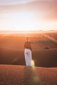 夕阳余晖中凝望沙海的女子