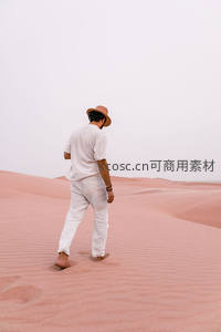 赤足行走在粉红沙丘上的男子
