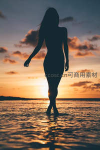 夕阳下海边漫步的女性剪影
