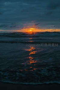 海浪中冲浪者剪影与落日余晖