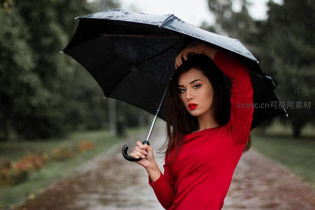 红衣女子雨中撑伞漫步林间小径