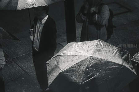 黑白雨中行人撑伞匆匆过街