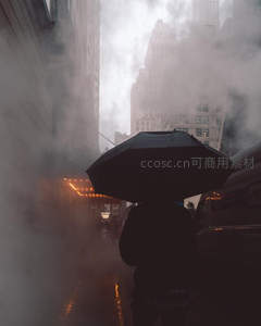 雾气弥漫都市街角，行人撑伞独行