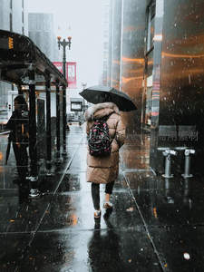 都市雨巷中撑伞前行的背影