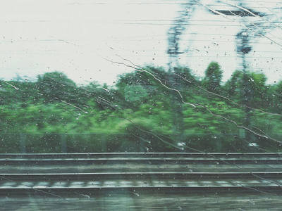 雨滴滑落车窗的模糊绿意