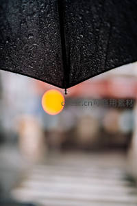 雨伞下悬垂水滴映暖光