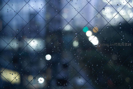 铁丝网后雨夜城市的朦胧灯火