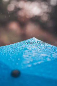 蓝色伞尖雨滴落，微距特写显晶莹