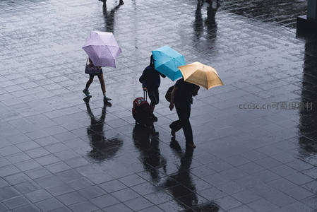 雨中行人撑伞漫步广场