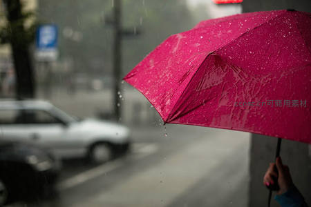街头红伞撑开，雨滴滑落如珠