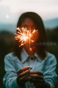 少女手持烟花棒遮住半张脸