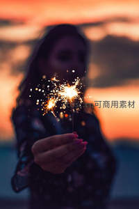 夕阳下女子手持烟花棒，光影朦胧